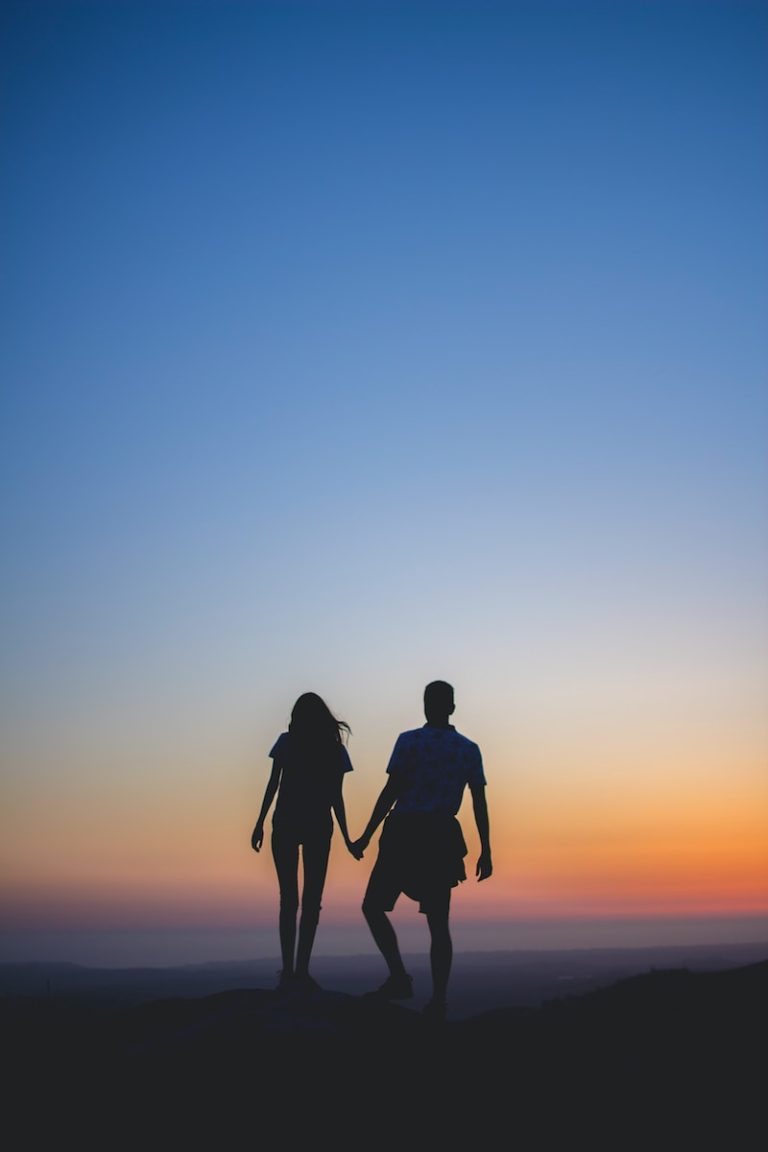 man and woman holding hands in silhouette photography